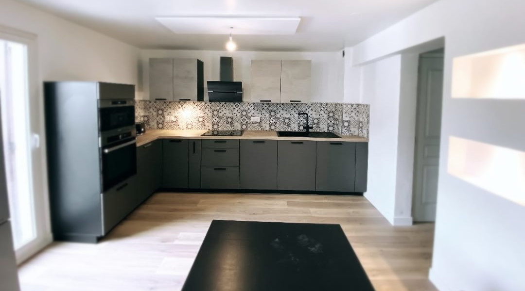 Cuisine moderne rénovée avec des meubles sur mesure, un plan de travail type chêne et un carrelage mosaïque.