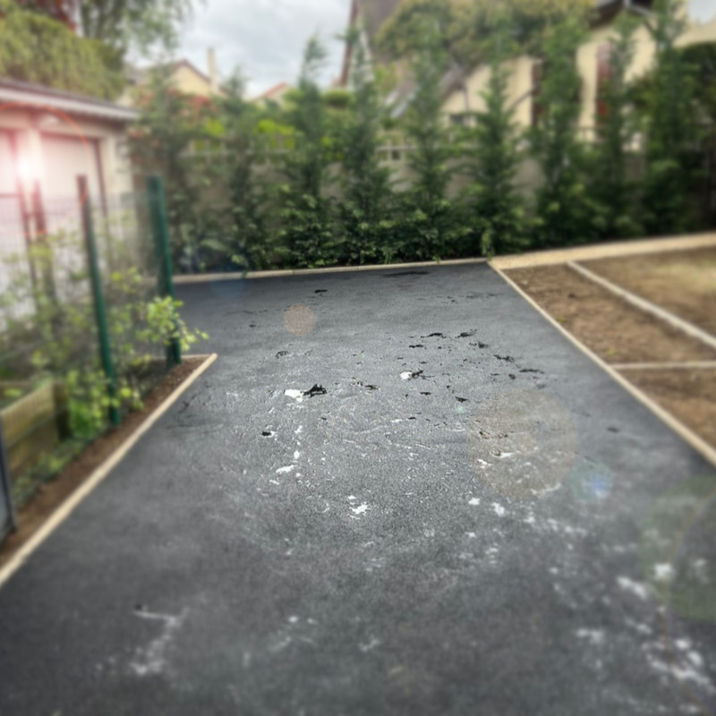 allée_en_enrobé Création d’une allée en enrobé noir dans une propriété située dans le Val d’Oise, bordée de clôtures et végétation.
