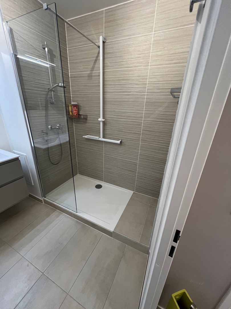 Salle de bain parmain Salle de bain rénovée sous combles avec baignoire îlot moderne, revêtement en carrelage beige et mosaïque murale.
